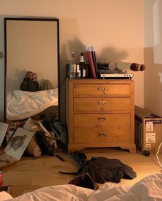 a person taking a selfie in a mirror next to a dresser and clothes on the floor