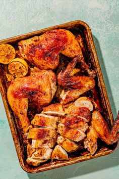 a roasting pan filled with chicken, potatoes and carrots on a blue surface