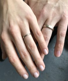 two people with their hands on each other's fingers, both wearing wedding rings