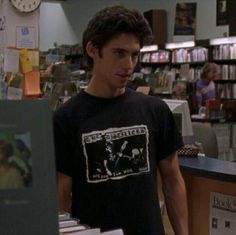 the young man is standing in front of books