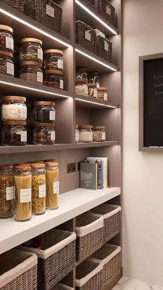 an organized pantry with lots of food in baskets and jars on the shelves next to a chalkboard