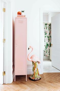 a flamingo statue sitting on top of a wooden floor next to a pink locker