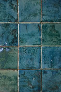 a blue and green tiled wall with some rust on the bottom half, in an area that looks like it could be used as a bathroom