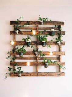 a wooden pallet filled with potted plants and lit candles on top of it