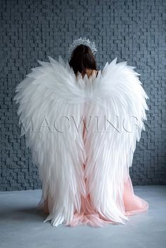 the woman is sitting down with her wings spread out and she has her back turned to the camera