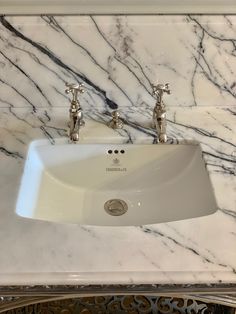 a bathroom sink with two faucets on the side and marble counter top above it