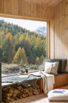 a living room filled with furniture next to a large window covered in forest view trees