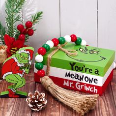 the grinch book is next to some christmas decorations and a pine cone with a tassel on it