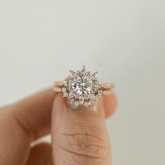 a woman's hand holding an engagement ring with three stones on it and the center diamond