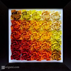 an art work with multiple colors of paper folded in squares and overlappingly arranged into the shape of spirals