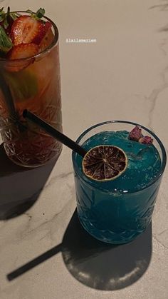 two glasses filled with drinks sitting on top of a table