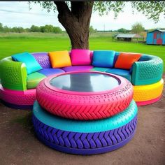 an unusual couch made out of old tires and other colorful furniture in a park setting