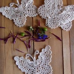 crocheted doily with flowers and butterflies on wooden floor next to each other