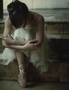 a woman is sitting on the steps with her hands in her lap and looking down