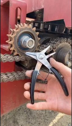 a person is holding scissors and pliers to the gear on a red truck's front end