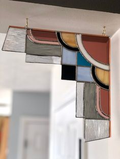a multicolored stained glass window hanging from the side of a wall in a house