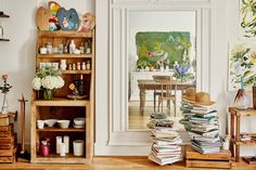 a living room filled with lots of furniture and books on top of wooden crates in front of a painting