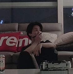 a man sitting on a couch talking on a cell phone next to a soda bottle