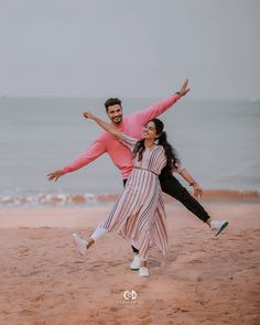 a man and woman are dancing on the beach with their arms around each other as they smile