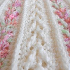 a white crocheted blanket with pink and green flowers