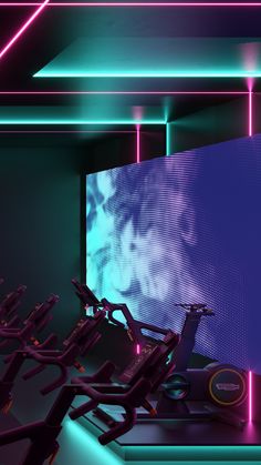 there are many exercise equipment in this room with neon lights on the wall behind them