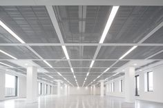 an empty white room with high ceilings and windows in the center is lit by recessed lights