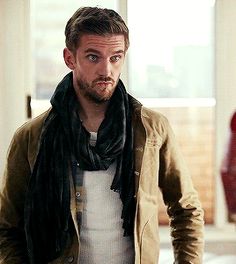 a man wearing a scarf and jacket standing in an empty room