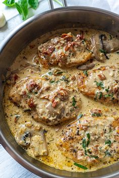 a pan filled with meat covered in gravy next to mushrooms and parsley