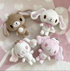 four stuffed animals sitting on top of a pink blanket