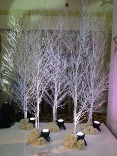 the table is set up with white trees and candles for an elegant event or celebration