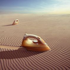 two irons sitting in the middle of a desert with sand dunes and blue sky