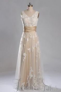 a dress on a mannequin with white flowers and gold ribbon around the waist