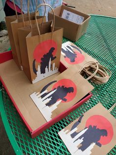 some brown paper bags sitting on top of a green table with red and white designs