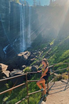 a woman is sitting on the steps near a waterfall and looking at the water from behind her