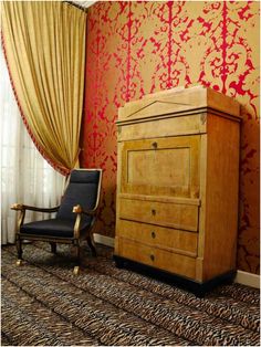 a chair and dresser in a room with red wallpaper