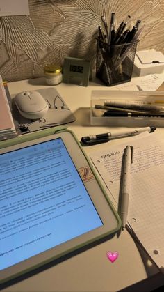 an open laptop computer sitting on top of a desk next to a pile of papers