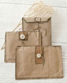 three pieces of brown paper with buttons and twine on them sitting next to each other