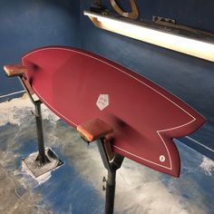 a red surfboard sitting on top of a stand in a room with blue walls