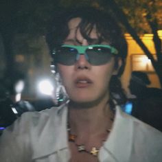 a woman wearing sunglasses is standing in the dark