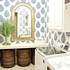 the bathroom is decorated with blue and white wallpaper, along with two wicker baskets