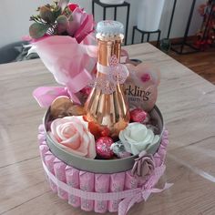 a wine bottle in a basket with pink roses and chocolates on the table next to it