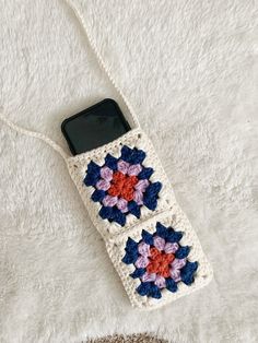 a crocheted cell phone case sitting on top of a white blanket