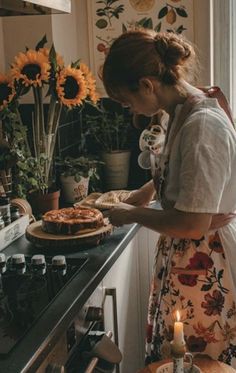 a woman standing in front of a stove with a pie on it's counter