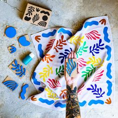 a person with tattoos on their arm is next to some wooden stamps and a bandana