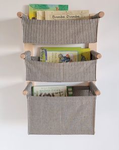 three bookshelves made out of wooden sticks and striped fabric, each holding different books