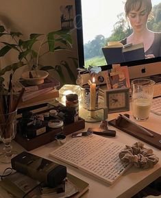 a desk with a computer monitor, keyboard and various items on it in front of a window