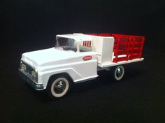 a white and red toy truck on a black surface with the back end facing away from the camera