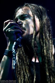a man with long dreadlocks on his face and holding a microphone to his mouth