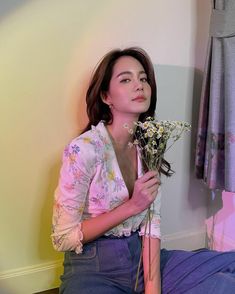 a woman sitting on the floor with flowers in her hand