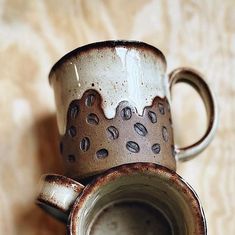 two coffee mugs sitting next to each other on top of a wooden tablecloth